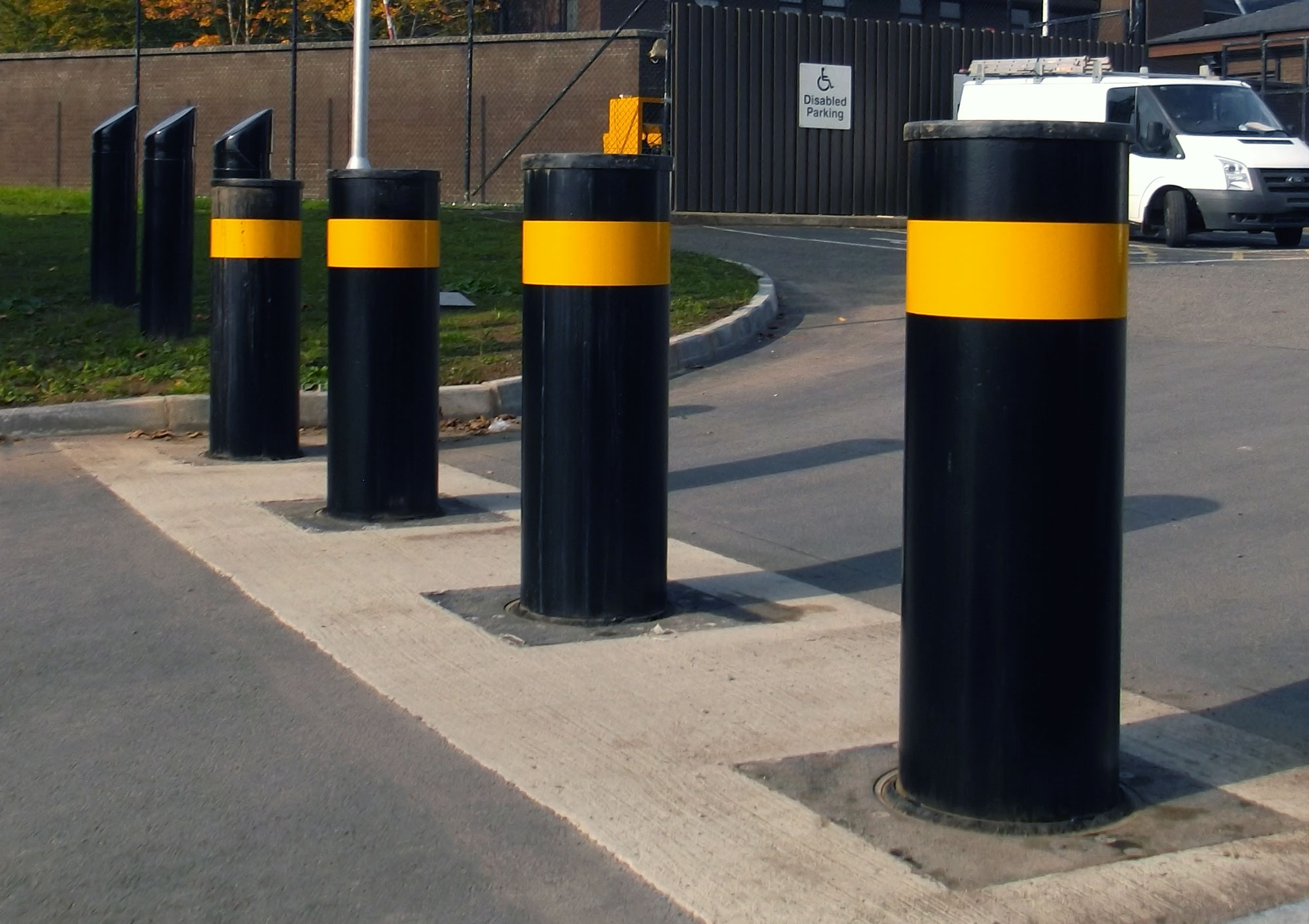 Black bollards with yellow bands around an access and parking area